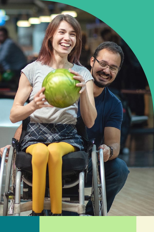 NDIS participant in a wheelchair bowling with her support worker